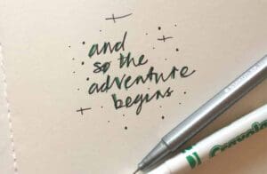 handwritten text on paper "and so the adventure begins"